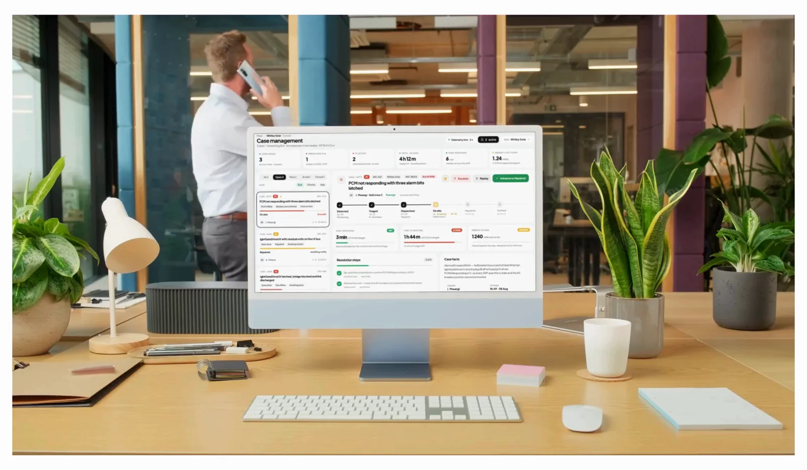 Case management open on a desktop in an office: three open cases on the left, one of them expanded through detected, triaged, dispatched and on site, with response and restore clocks against their targets, while someone takes a call in the background